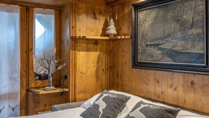 L’intérieur d’un chalet en bois, avec un lit, un tableau encadré et un plafond en bois.