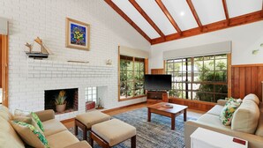 A living room with a fireplace, a television, and large windows. - Time and Tide in Inverloch (Inverloch)