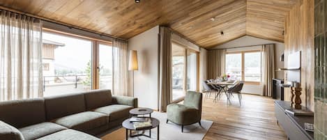 Un vaste espace de vie doté d’un plafond en bois, d’un canapé, d’une table basse et d’un coin repas avec une table et des chaises.