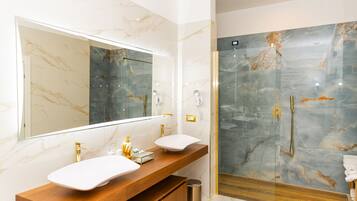 Une salle de bain moderne avec un grand miroir, deux lavabos, un espace douche et des murs en marbre.
