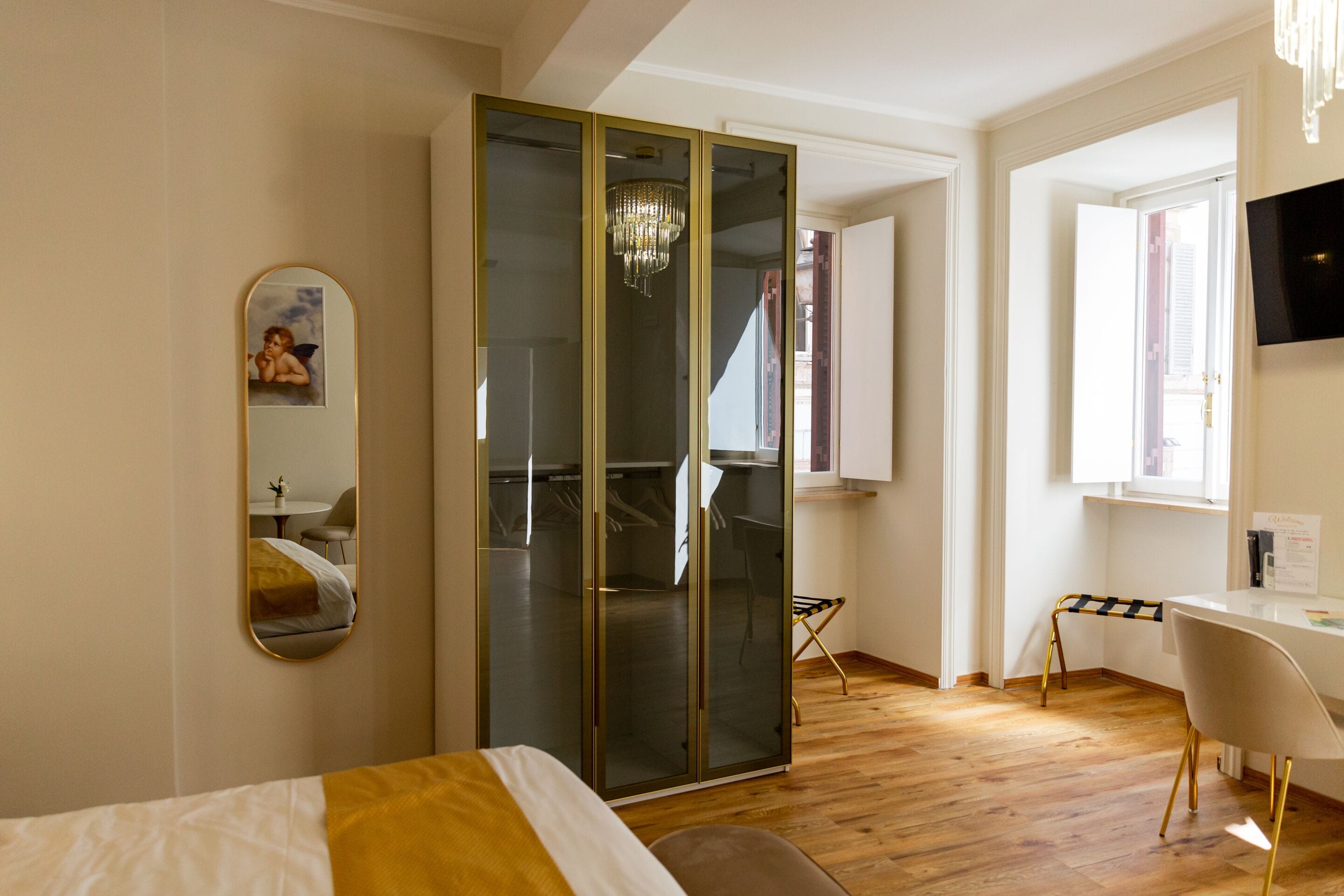 Quarto de hotel moderno com cama, escrivaninha, cadeira, guarda-roupa e espelho.