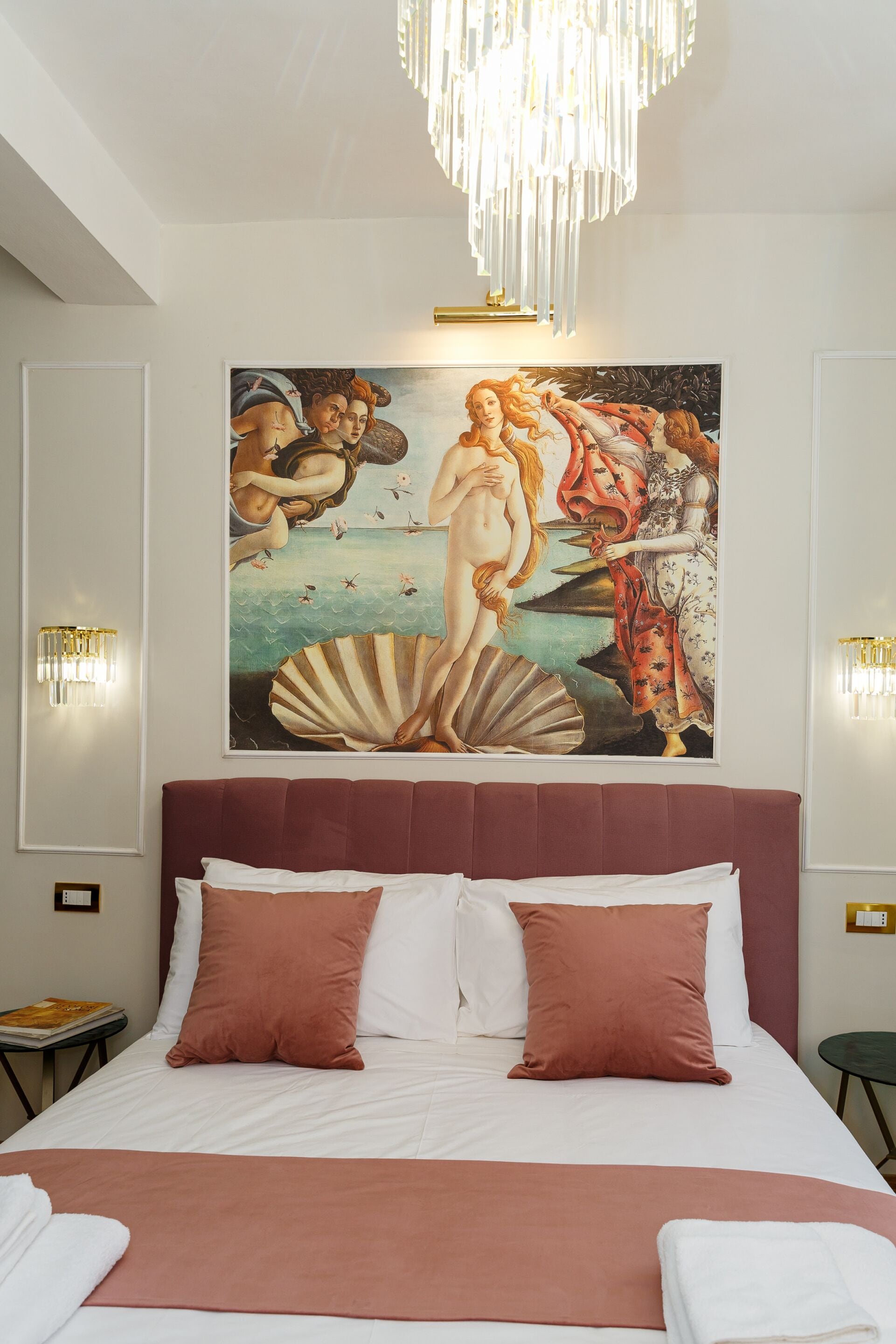 Un dormitorio con una cama grande, un cuadro en la pared y dos apliques.