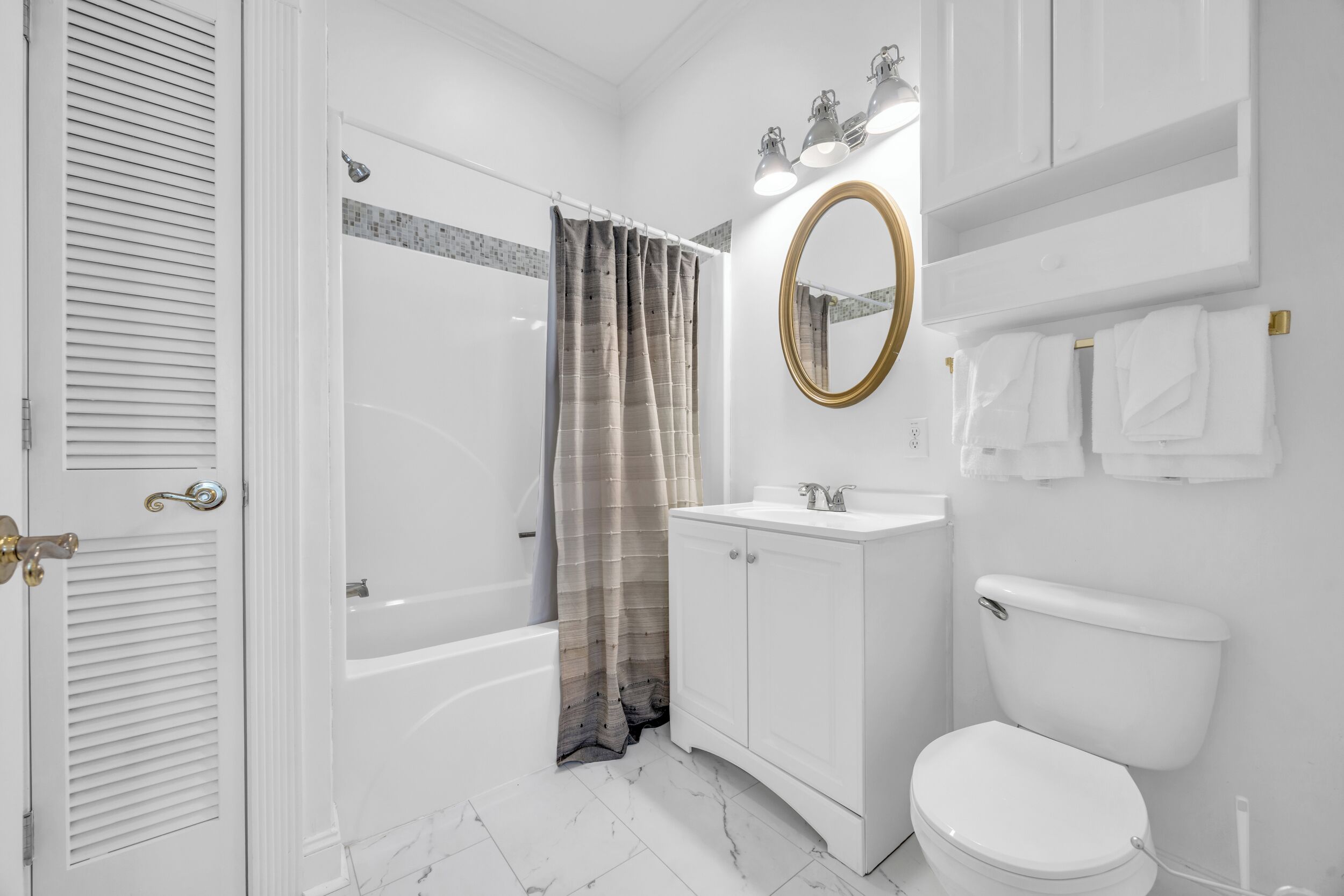 Un bagno moderno con vasca, WC, mobile lavabo e tenda per la doccia.