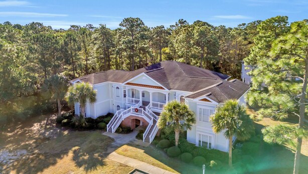 A two-story house with a wrap-around porch, a brick entrance, and a well-maintained lawn.
