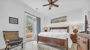 A bedroom with a wooden bed, a wicker chair, a dresser, and a ceiling fan.