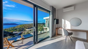 Ein modernes Zimmer mit einer großen Schiebeglasdoor zu einem Balkon mit Blick auf eine reizvolle Landschaft.