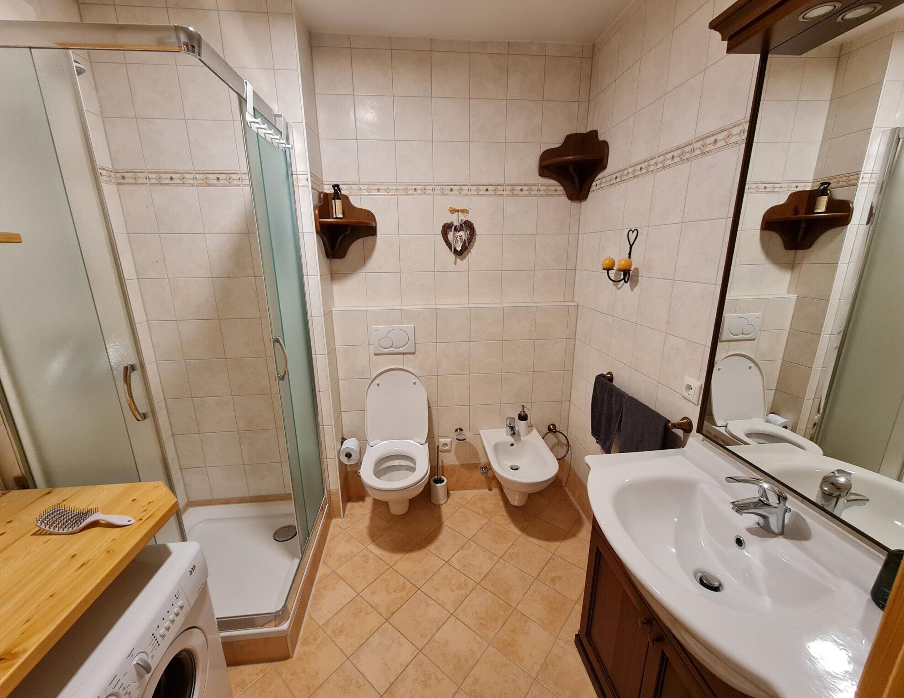 A bathroom with two toilets, a sink, a mirror, and a shower.