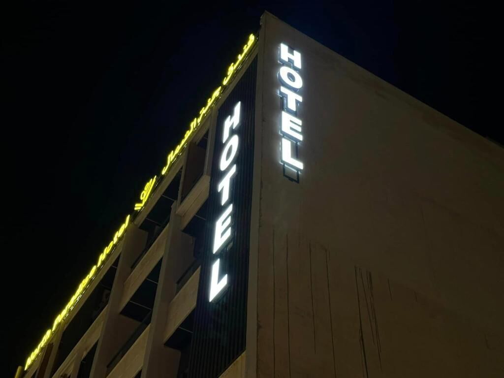 Letrero de hotel con la palabra 'HOTEL' iluminada en letras blancas sobre un cielo oscuro.
