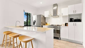 Una cocina moderna con armarios blancos, electrodomésticos de acero inoxidable, una isla grande con taburetes y vistas al exterior.