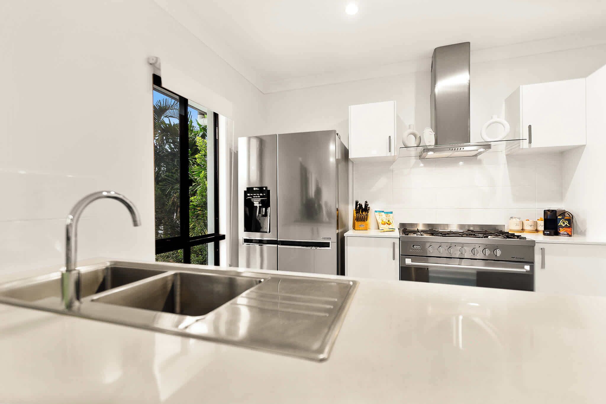 A modern kitchen with stainless steel appliances, a double sink, and a gas stove.