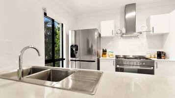 A modern kitchen with stainless steel appliances, a double sink, and a gas stove.