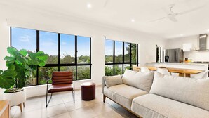 Una sala de estar moderna con un sofá, un sillón y un ventanal con vistas a la vegetación.