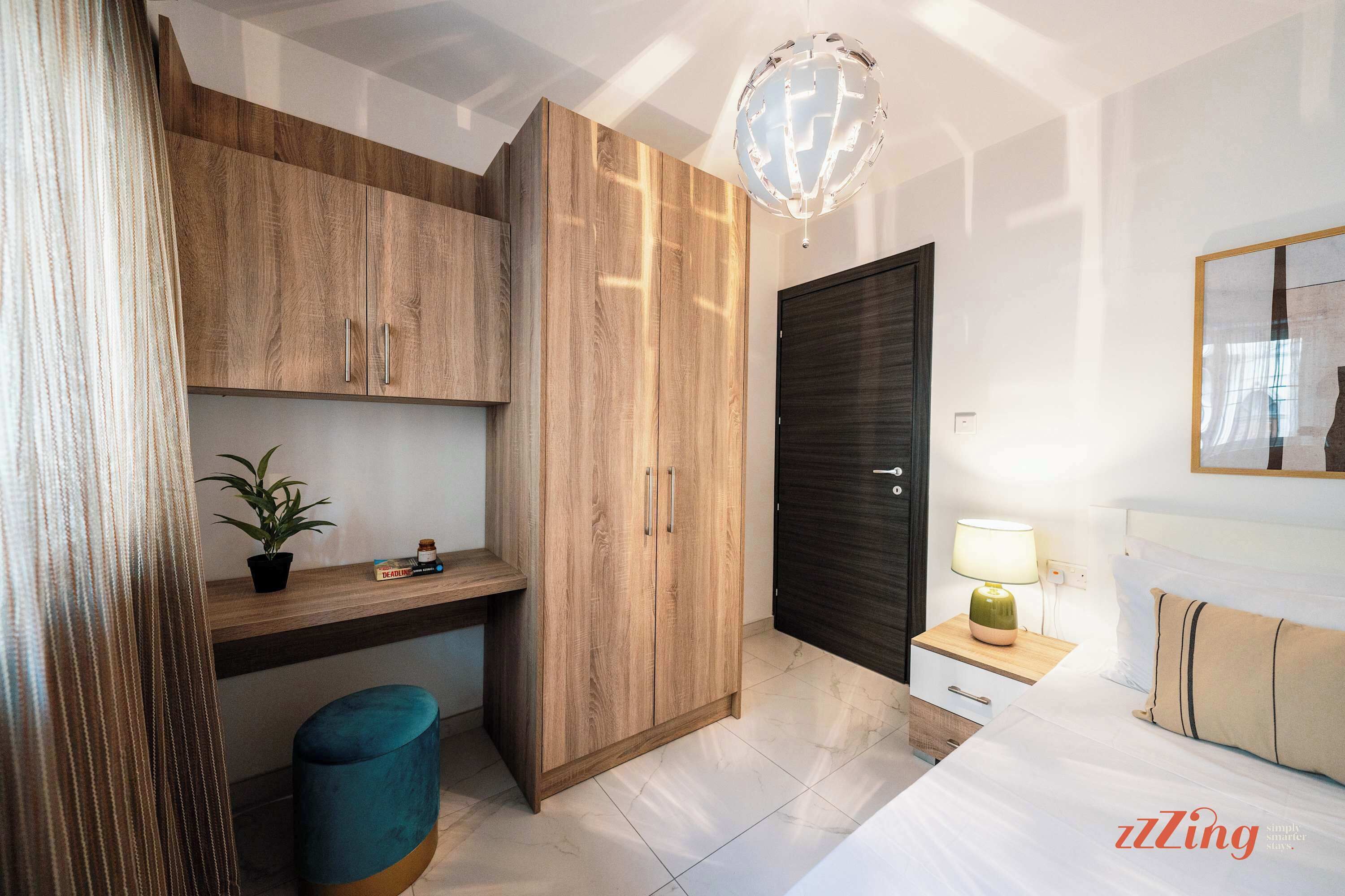 A modern bedroom with a bed, bedside table, lamp, and wardrobe.