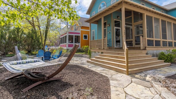 Une maison avec une véranda, un hamac et des meubles d’extérieur.