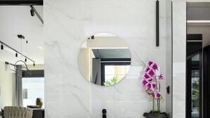 Un baño moderno con tocador negro, un espejo redondo y una orquídea en maceta.