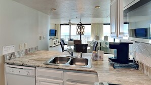 Een moderne keuken met een dubbele spoelbak, een ingebouwde vaatwasser en een eethoek met uitzicht op zee.