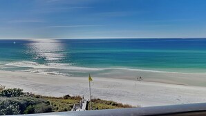 Een strand met een vlag, heldere lucht en een rustige zee.