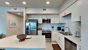 A modern kitchen with white cabinets, stainless steel appliances, and a central island.