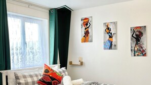A neatly arranged bedroom with a bed, a bedside table, and a window with curtains. - The Express Apartment (Ilford)