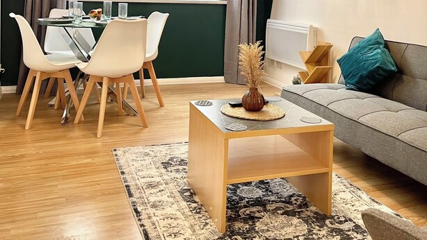 A modern living room with a dining area, a sofa, and a coffee table. - The Express Apartment (Ilford)