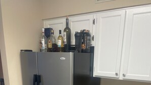 Eine Küche mit einem Edelstahl-Kühlschrank, weißen Schränken und Holzboden.