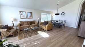 A spacious living room with a sofa set, a coffee table, and a dining area with chairs and a table. - 4 Bedroom Villa with Private Pool & Golf Course Views (Haines City)