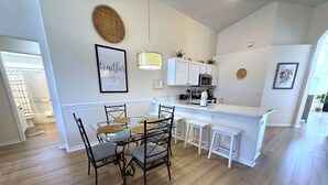 A modern kitchen with white cabinets, a central island with stools, and a dining table with chairs. - 4 Bedroom Villa with Private Pool & Golf Course Views (Haines City)