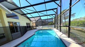 An indoor swimming pool with a glass ceiling, surrounded by a poolside area with lounge chairs and a view of the outdoors. - 4 Bedroom Villa with Private Pool & Golf Course Views (Haines City)