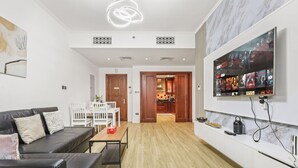 A modern living room with a leather sofa, a dining table, and a kitchen area visible through an open door. - Cozy 1BR Apartment | Close to Mall, Metro, and Dining (Dubai)