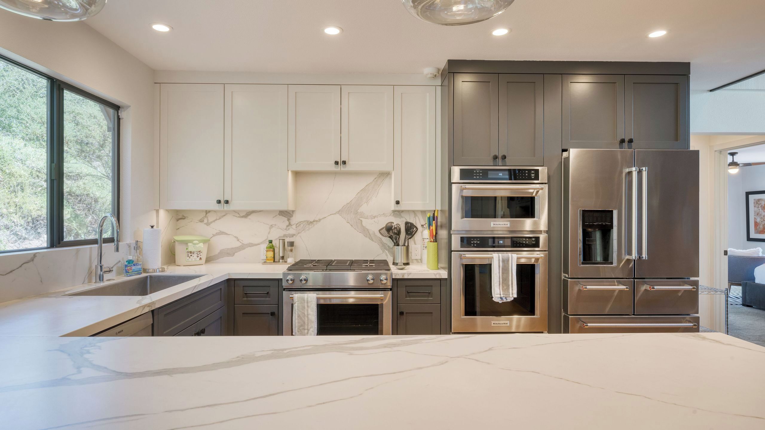 A modern kitchen with a large island, built-in appliances, and a view of the outdoors.