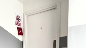 A white door with a number '2' above it, a red emergency kit sign, and a metal handle. - Norwich Delight Apartment (Romford)