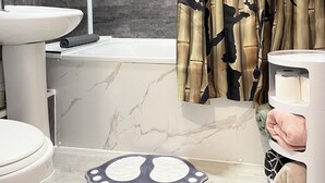 A bathroom with a modern design, featuring a marble sink, a toilet, and a shower area. - Norwich Delight Apartment (Romford)