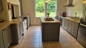 A modern kitchen with a central island, stainless steel appliances, and a large window providing a view of the garden.