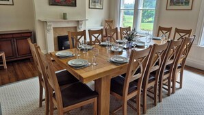 A dining room with a large wooden table set for a meal, surrounded by wooden chairs.