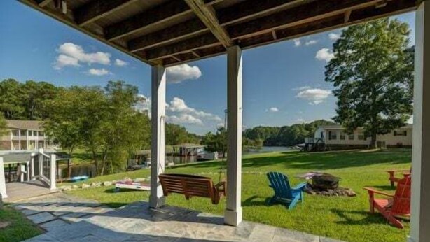 Ein überdachter Patio-Bereich mit Steinboden, einer Bank und Gartenmöbeln.