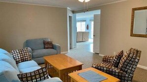 Ein Wohnzimmer mit Sofa, Sessel, Couchtisch und Deckenventilator.