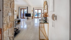 A spacious living area with a stone wall, a flat-screen TV, a large mirror, and a phone on the wall. - Hg07 Adjacent to Aphrodite Hills- Private Pool, Large Terrace (Kouklia)