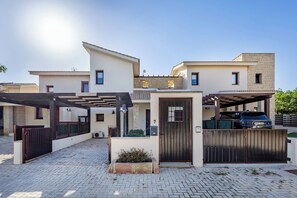A modern two-story house with a garage, a covered driveway, and a well-maintained garden area.