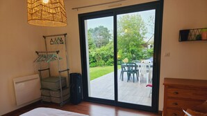 A bedroom with a bed, a wardrobe, a hanging rack, a suitcase, and a view of an outdoor patio with a table and chairs. - Large family home (Combrit)