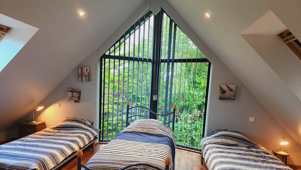 A dormitory room with two beds, wooden flooring, and a large window with a view of greenery. - Large family home (Combrit)