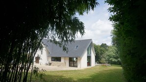 A modern house with a sloped roof, large windows, and a spacious front yard. - Large family home (Combrit)