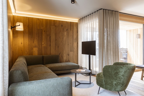 A modern living room with a sectional sofa, a round coffee table, and a green armchair. - Apartment in Westendorf With Infrared Sauna (Westendorf)