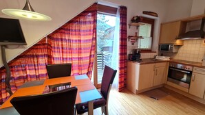 Una cocina con armarios de madera, horno empotrado y comedor con mesa y sillas.