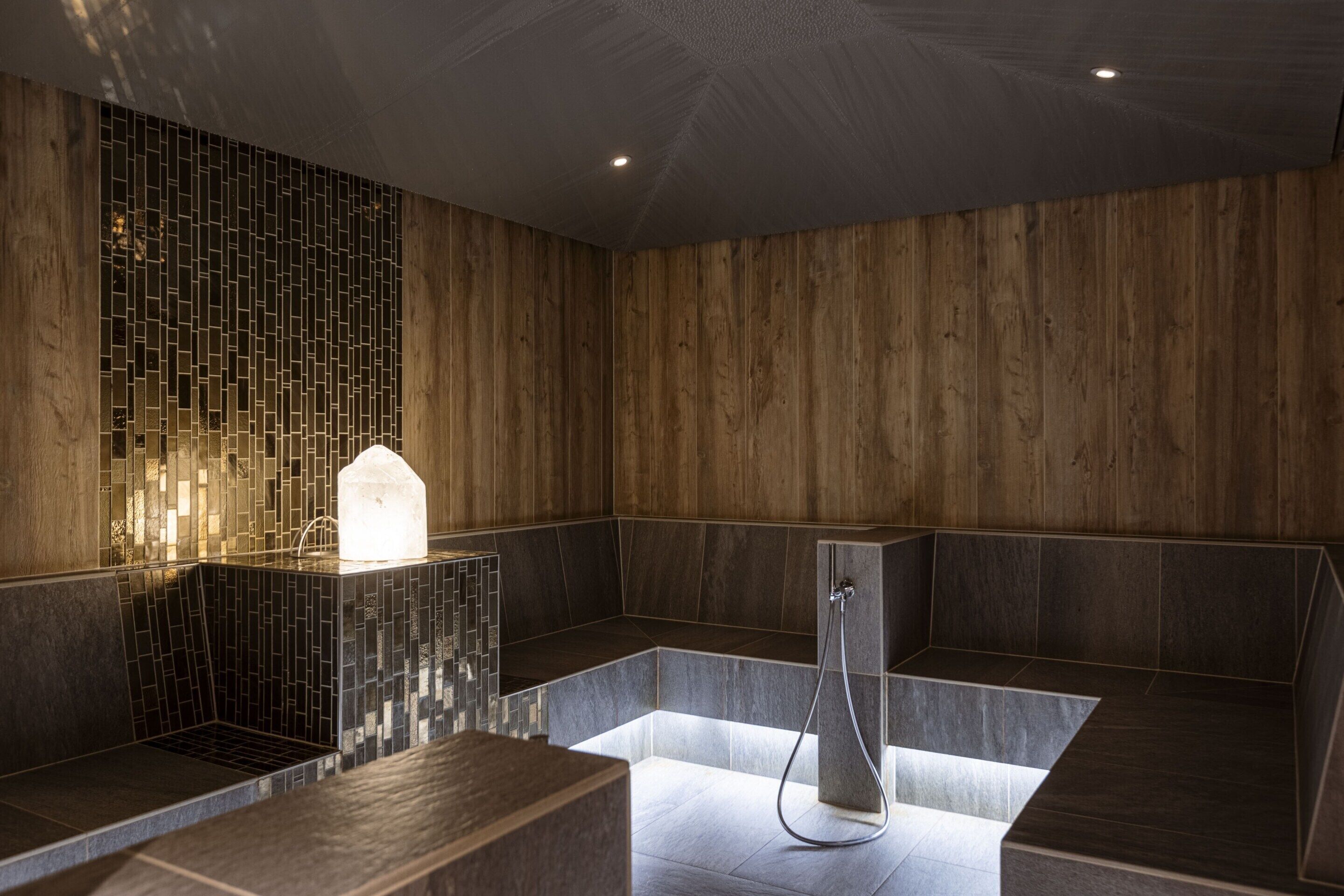 A modern bathroom with a wooden wall, a tiled sink area, and a shower with a handheld showerhead.