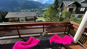 A wooden deck with two chairs and a table, overlooking a mountainous landscape. - Apartment With Carinthian Mountain View (Bad Kleinkirchheim)