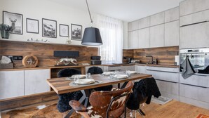A modern kitchen with a wooden dining table, black chairs, and a hanging light fixture. - Apartment With Carinthian Mountain View (Bad Kleinkirchheim)