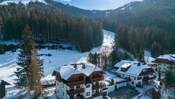 A snow-covered mountain resort with wooden buildings, a ski slope, and a forested valley. - Apartment With Carinthian Mountain View (Bad Kleinkirchheim)