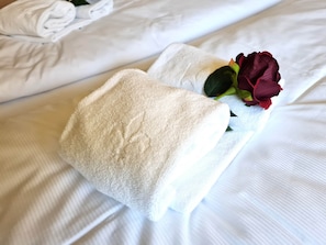A neatly made bed with white linens and a single red rose placed on the pillow. - Beautiful Apartment in Bad Kleinkirchheim (Bad Kleinkirchheim)
