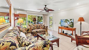 A living room with a sofa, coffee table, TV, and a ceiling fan. - Remodeled, A/C,-KS C2C - Sullivan Properties (Lahaina)