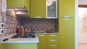 Une cuisine avec des meubles de couleur verte, un plan de travail blanc et un pare-feu en carreaux.